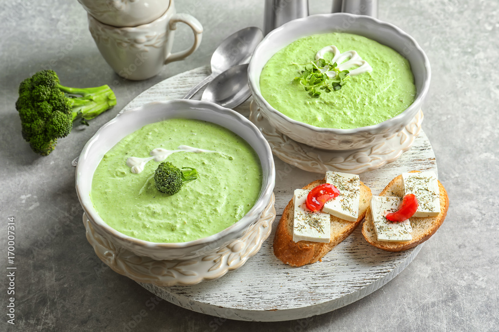 Bowls with delicious broccoli soup on wooden tray Bowls with delicious broccoli soup on wooden tray