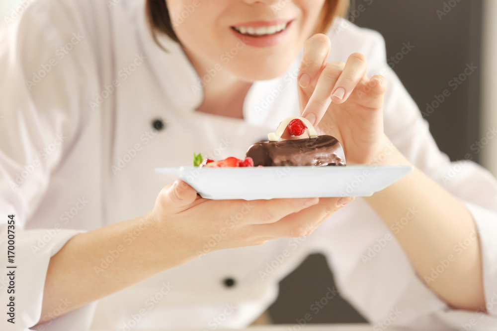 Female chef decorating tasty dessert in kitchen, closeup Female chef decorating tasty dessert in kitchen, closeup