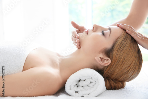 Young woman enjoying of facial massage in spa salon