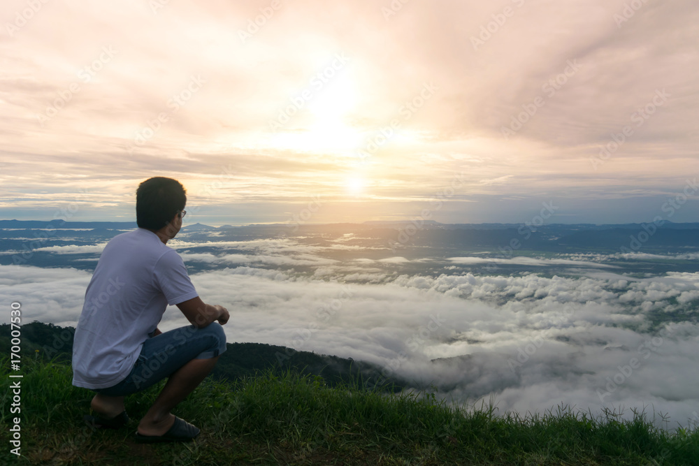 Man sitting morning sun in mist and fog scenery mountain background