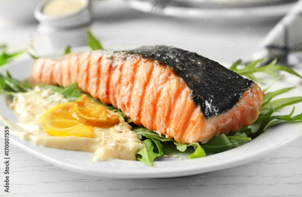 Plate with slice of delicious grilled salmon and fish sauce on table Plate with slice of delicious grilled salmon and fish sauce on table