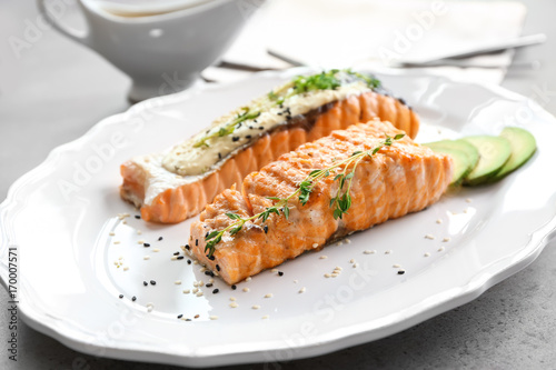 Plate with delicious salmon and fish sauce on table