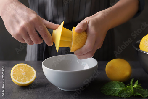 Obraz na plátně Man extracting lemon juice with plastic citrus reamer