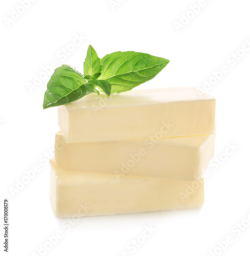 Cut block of butter with fresh basil leaves isolated on white