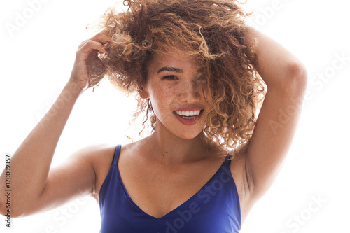 Portrait of a smiling and curly woman with freckles.