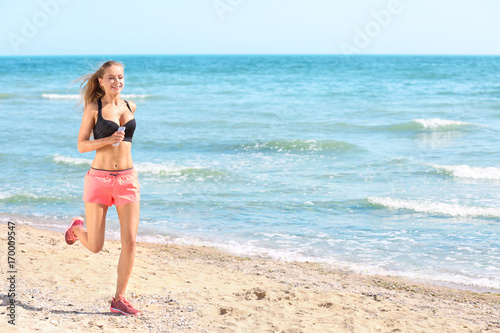 Beautiful young woman running on sea beach