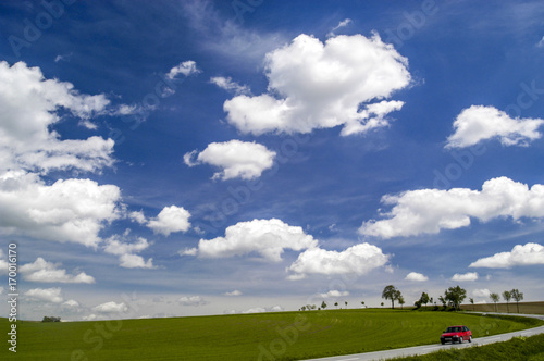 Kurvige Strasse, Allee, Felder, tiefhängende, weisse Wolken am