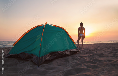 Happy time for camping at the beach sunset sky. Girl looking at the sea