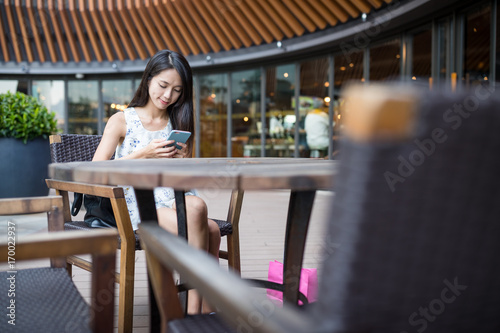 Woman sending sms on cellphone in coffee shop