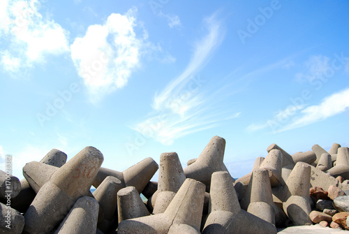 Obraz na plátne Concrete jetty surrounded by rocks - clear blue sky