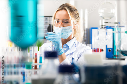 Young attractive female scientist preparing laboratory equipment for tests