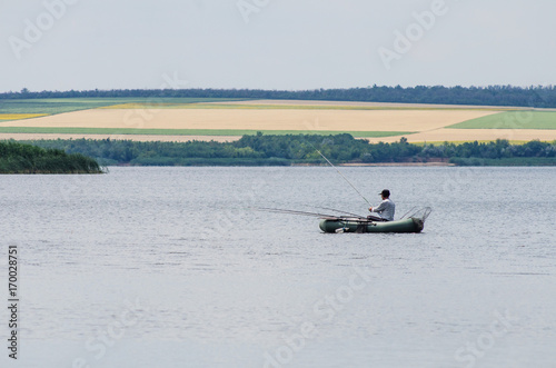 The fisherman on a boat catches fish on a pond