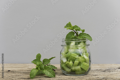 Green celery in jar and fresh mint leaf on wood table for green smoothie photo