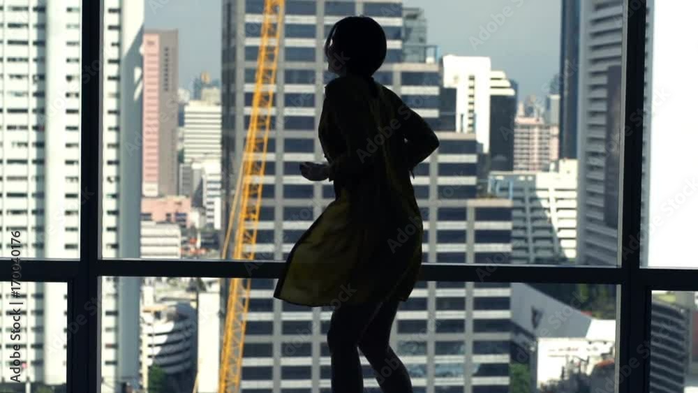 Silhouette of woman in shirt dancing by window at home
Silhouette of woman in shirt dancing by window at home