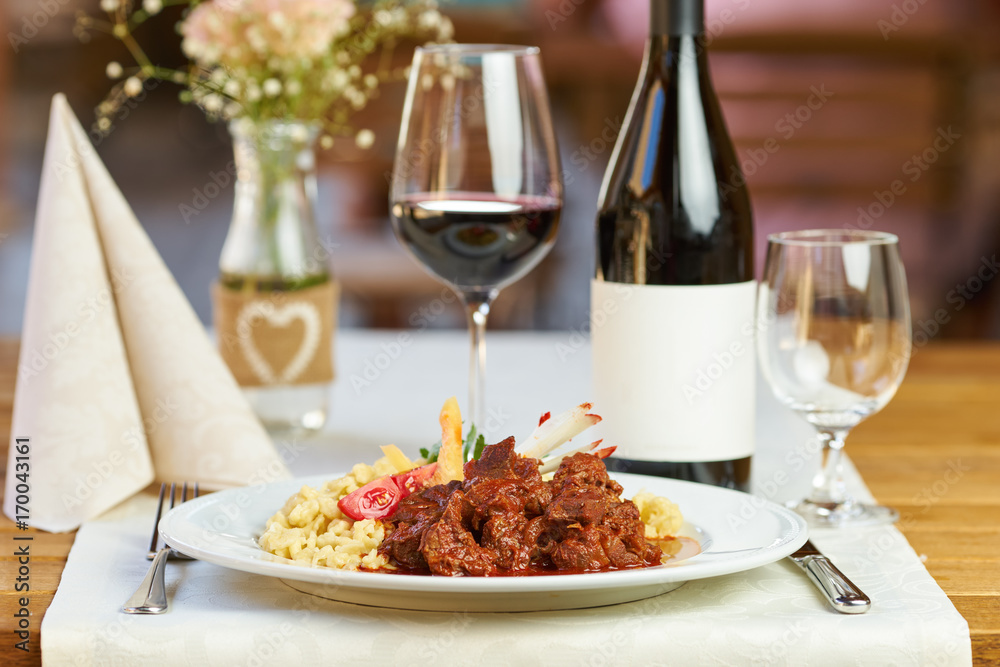Beef stew in a restaurant with red wine in the background Beef stew in a restaurant with red wine in the background