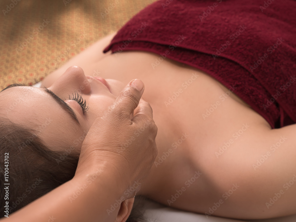 Young beautiful lady laying down with dark red towel wrap the body for face massage