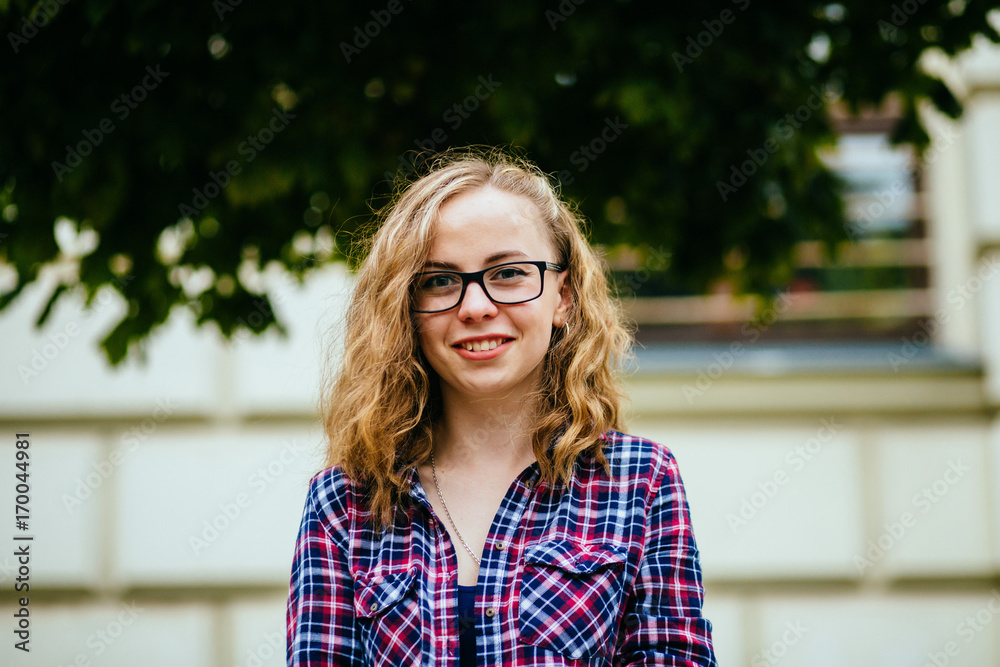 Portrait of young woman smiling with glasses against a plants background - - education, school, teamwork and people concept. Portrait of young woman smiling with glasses against a plants background - - education, school, teamwork and people concept.