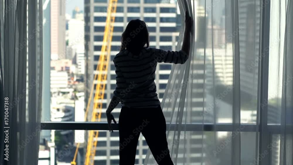 Silhouette of woman unveil curtains from window at home
Silhouette of woman unveil curtains from window at home