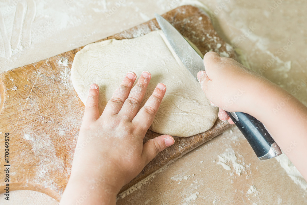 A child cuts the raw dough