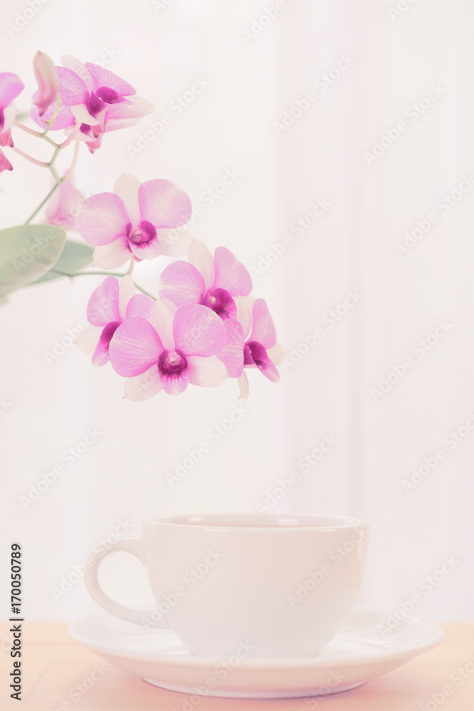 Coffee cup and beautiful purple orchid flowers on wood table over soft white background,pastel filter