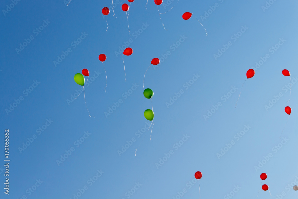 Balloons. The children released a lot of balls with ropes in the sky.Red and green balloons in the blue sky in the rays of the sun. Balloons. The children released a lot of balls with ropes in the sky.Red and green balloons in the blue sky in the rays of the sun.
