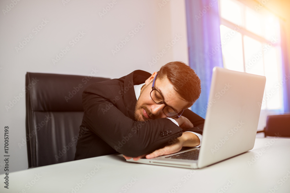 Young businessman asleep on desk work with laptop Young businessman asleep on desk work with laptop