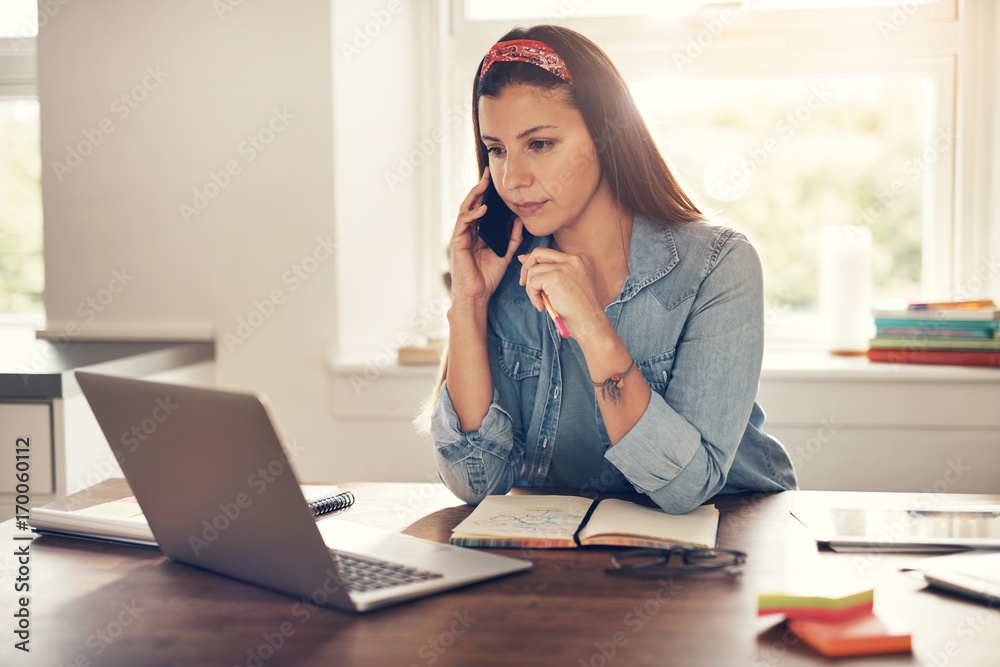 Employee woman talking smartphone and looking at laptop Employee woman talking smartphone and looking at laptop