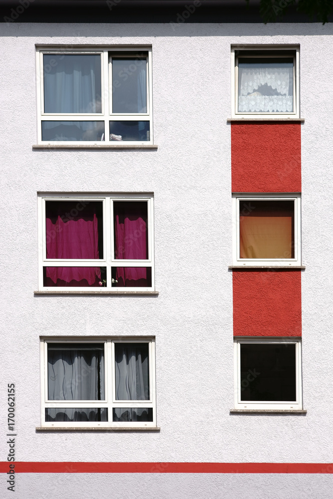 Wohnungsfenster mit bunten Gardinen  / Die Fenster eines mehrstöckigen Wohnhauses mit bunten Gardinen und buntem Anstrich.