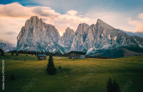 Alpe di Siusi (Seisser Alm) meadows and traditional old mountain chalets with mountains in the background in the moonlight. Trentino Alto Adidge, Italy.