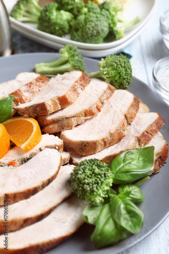 Plate with delicious sliced turkey fillet and orange on table, closeup