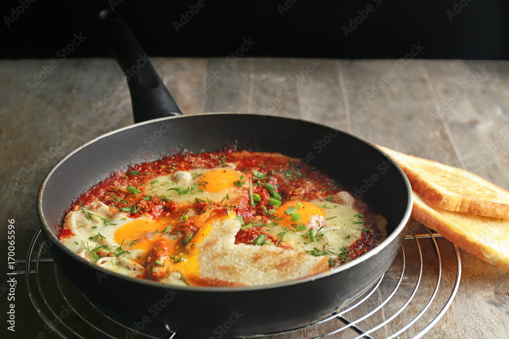 Frying pan with eggs in purgatory on table