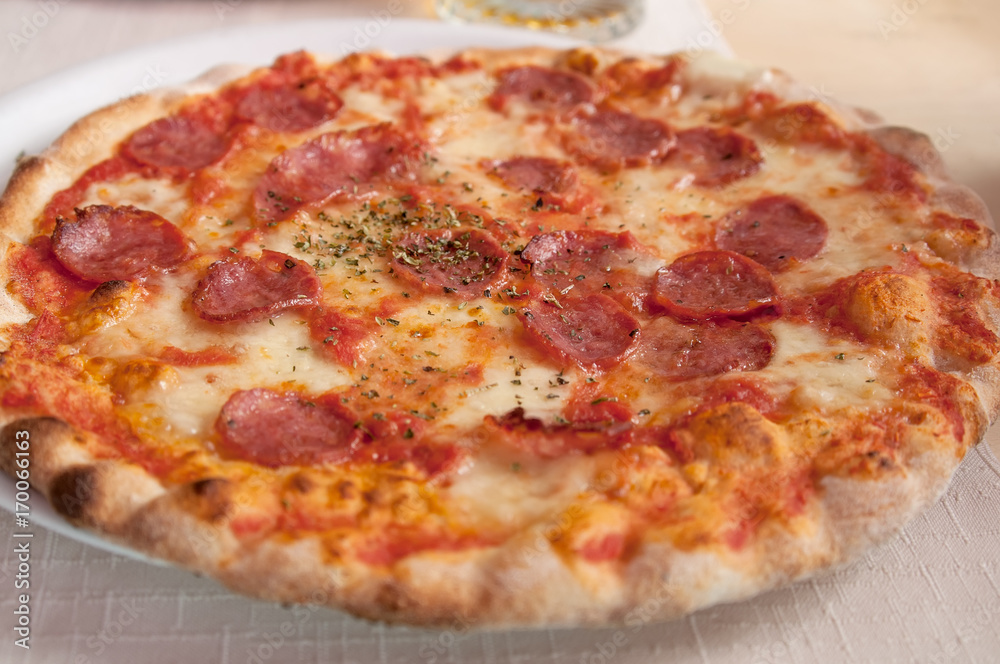 Round sausage pizza Margherita on a white plate. Selective focus.