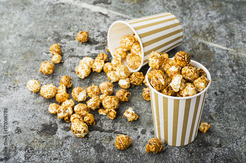 Appetizing homemade caramel popcorn in striped classic paper cups on a gray background. Selective focus. photo