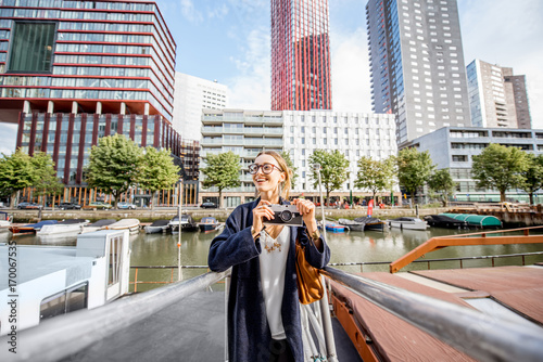 Young woman traveling at the modern harbor with skyscrapers on the background in Rotterdam city