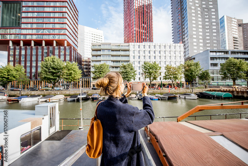 Young woman photographing modern skyscrapers standing on the harbor in Rotterdam city