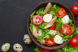 Fresh salad caesar with chicken, quail eggs, tomatoes and lettuce in a bowl
