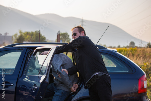 Arresting a thief, a criminal, a drug dealer with hands armed with police cuffs, a thief disabled, Two policemen lead him and lead him to the car