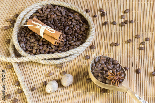 Coffee beans in a ring of hemp, star anise on the background bamboo Mat. Next to the wooden spoon with allspice.