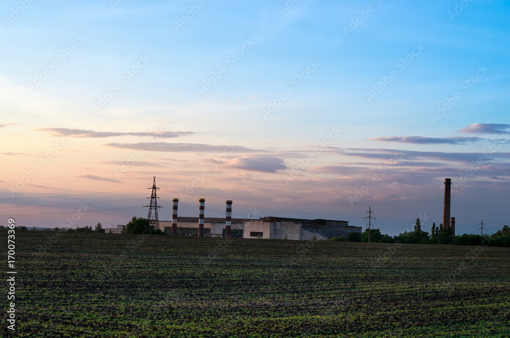 Factory with chimneys in the distance against the sunset Factory with chimneys in the distance against the sunset