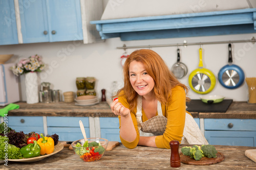 Foxy housewife in the kitchen. Mid aged female cooking helthy food.