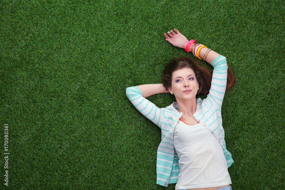Beautiful redhead women lying down on green grass in summer time in the park Beautiful redhead women lying down on green grass in summer time in the park