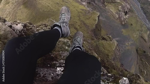 A hiker dangles his legs over the edge of a cliff