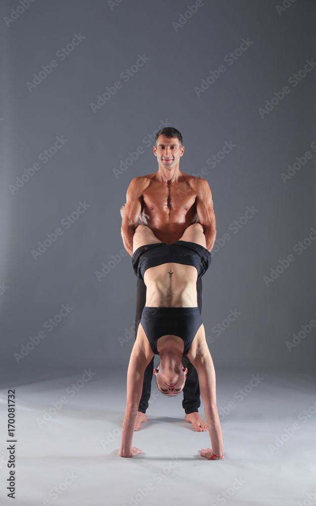 Obraz premium Young couple practicing acro yoga on mat in studio together. Acroyoga. Couple yoga. Partner yoga.