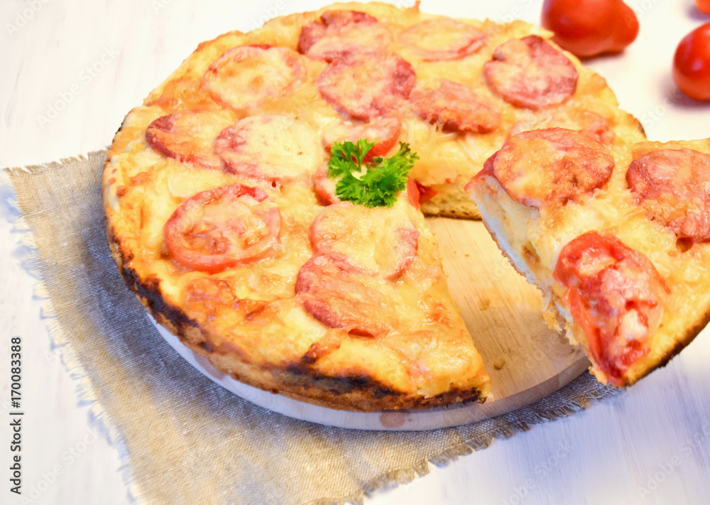 homemade pizza with tomatoes, salami and cheese
