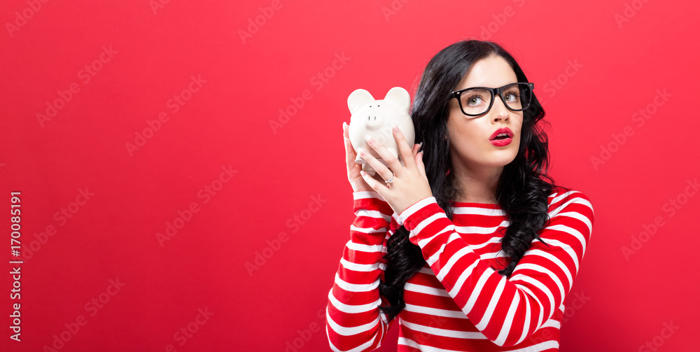 Young woman with a piggy bank on a red background Young woman with a piggy bank on a red background