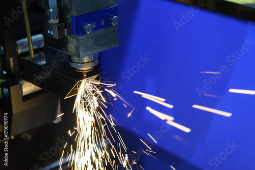 The CNC fiber laser cutting machine cutting the steel square pipe with the sparking light.The fire flame from the fiber laser cutting machine.