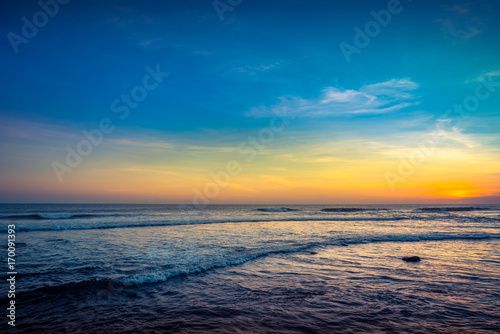 Blue Waves near sea Resort. Isolated Sea Sunset. Surfing Beach with Surfers on the Horizon. Landscape. Sunset Background Ocean. Tropical Sunlight and Summer Sunset View. Colorful Background Sunset. 