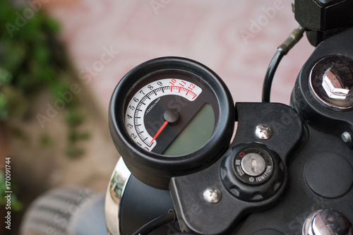 Speedometer on motorcycle dashboard. Round speedometer with red arrow. Speed zero shown.