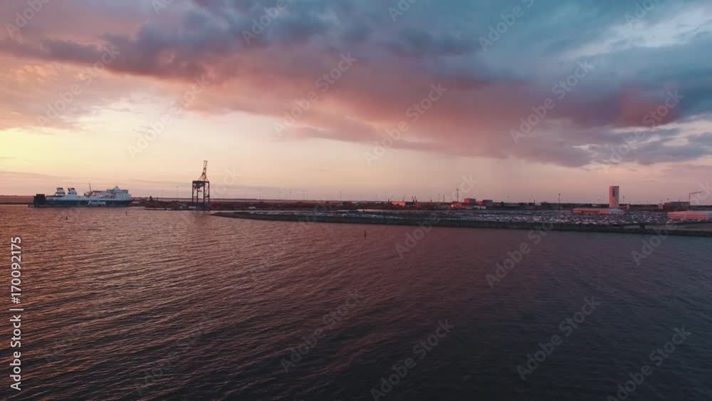 Aerial view of sea and cargo container terminal harbor in the distant at sunset. Ship at the dock Aerial view of sea and cargo container terminal harbor in the distant at sunset. Ship at the dock