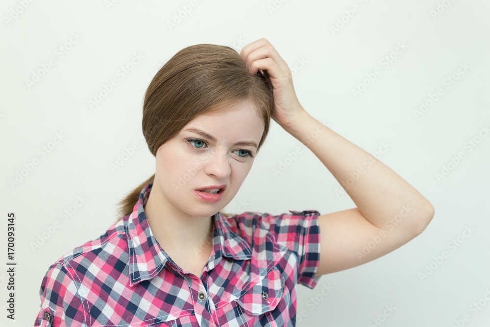 Caucasian girl scratching her head, thinking of something, looks bewildered Caucasian girl scratching her head, thinking of something, looks bewildered